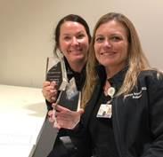 two awards program attendees holding a gift basket